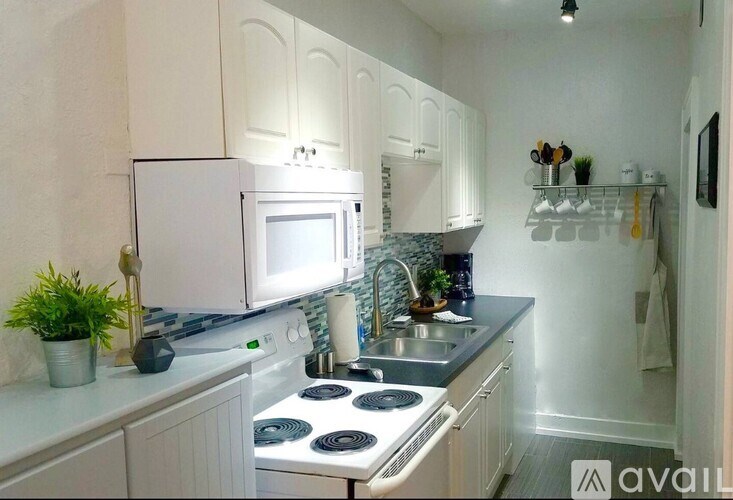 A kitchen with white cabinets and a white fridge.