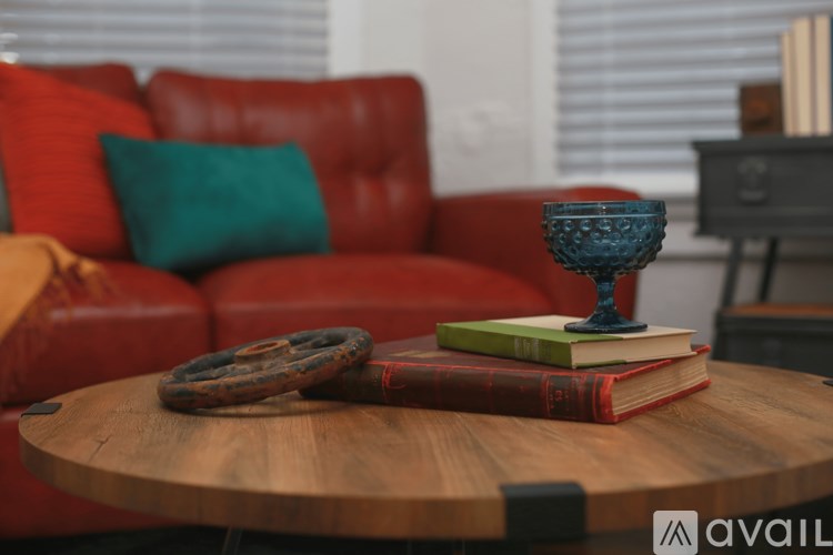 A red couch with a blue vase on a wooden table.