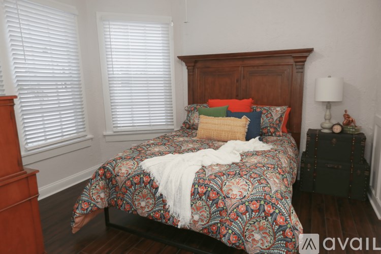 A bed with a wooden headboard and a patterned comforter is in the image.