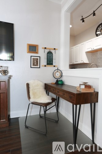 A chair with a white furry seat sits in front of a desk with a mirror behind it.