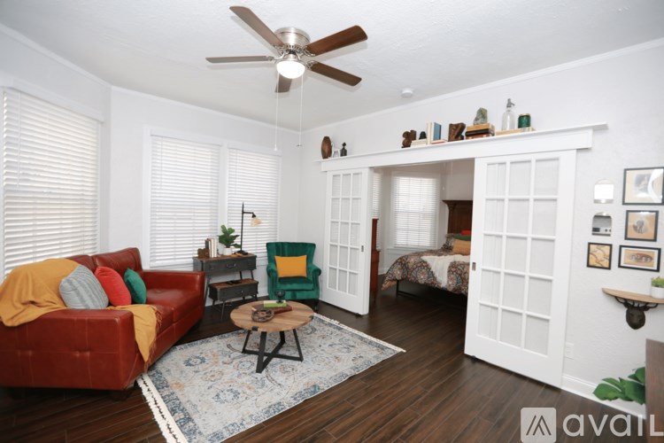 A living room with a red couch, a green chair, and a ceiling fan.