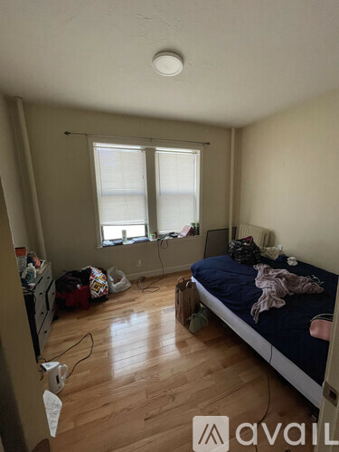 A bedroom with a bed, dresser, and window.