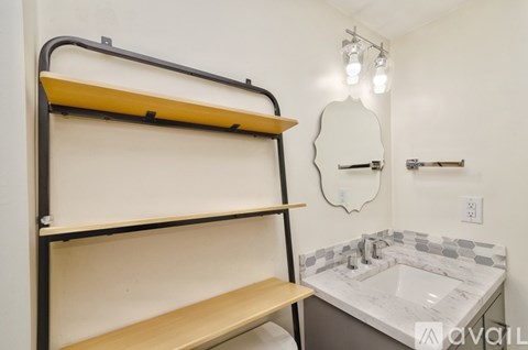 A bathroom with a marble countertop and a mirror above it.