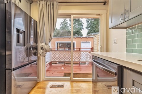 A kitchen with a refrigerator, oven, and a view of a balcony.