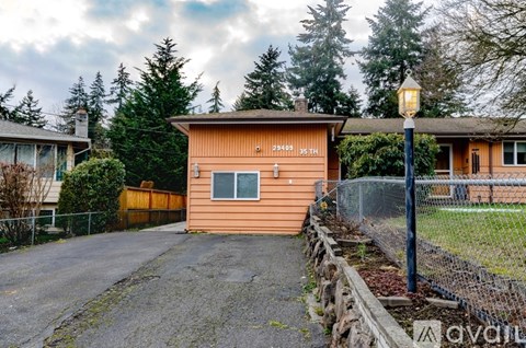 A small orange building with a sign that reads "2940 35TH" sits in front of a fence and trees.