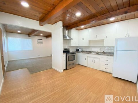 A kitchen with white cabinets and a wooden ceiling.