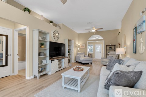 A living room with a white couch and a television on the wall.