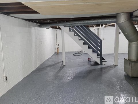 A concrete staircase in a basement with a metal railing.
