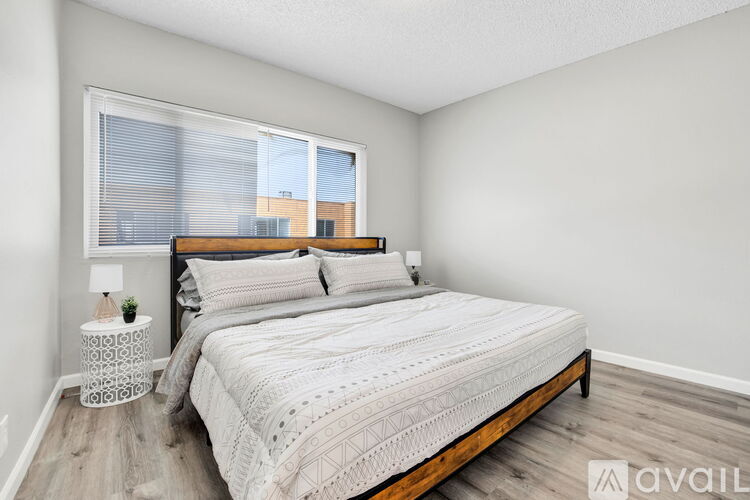 A bedroom with a large bed and a small table with a lamp on it.