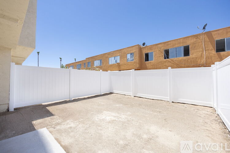 A white fence surrounds a brown building with a clear blue sky in the background.