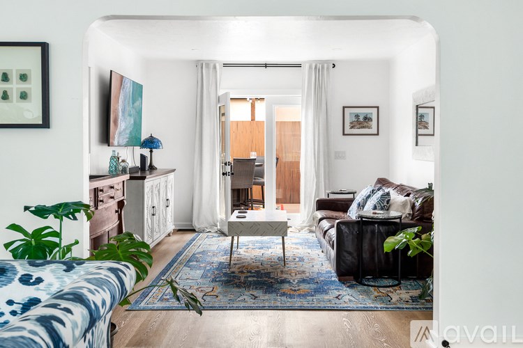 A living room with a blue patterned sofa and a rug.