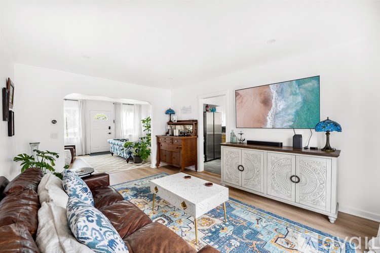 A living room with a brown leather couch and a white coffee table.