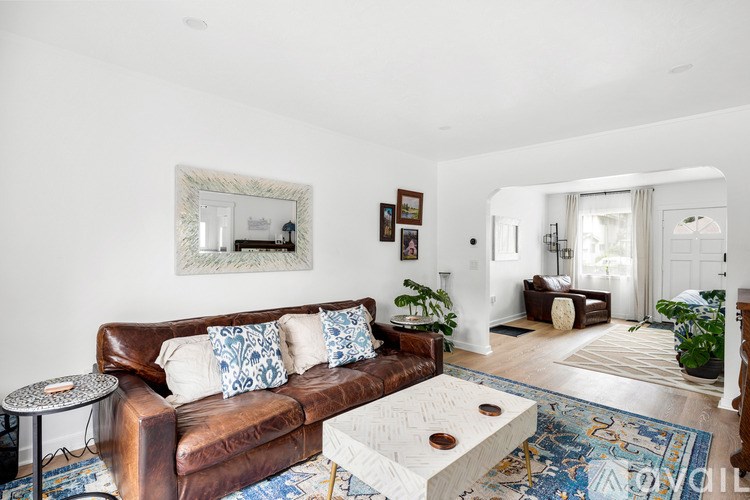 A living room with a brown leather couch and a white coffee table.