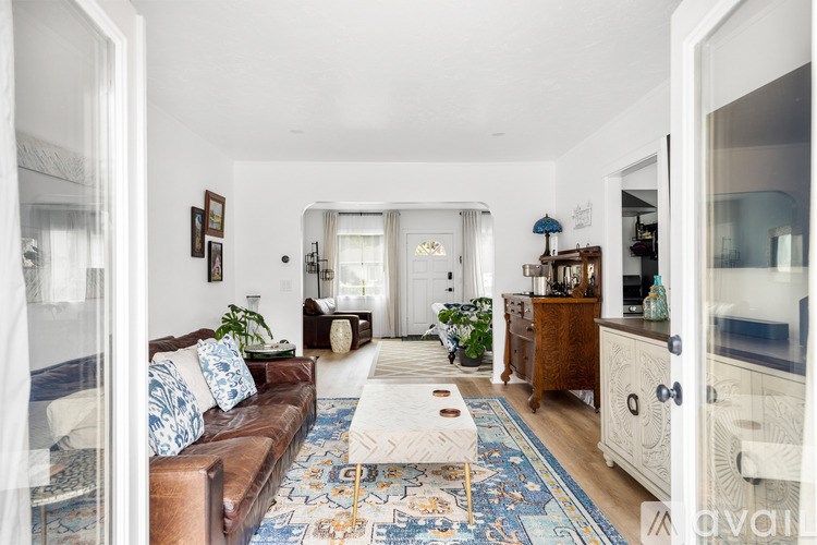 A living room with a brown couch and a rug.