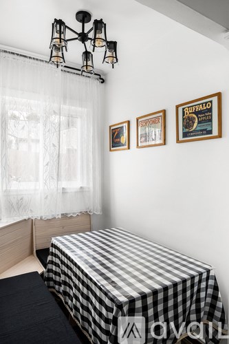 A bedroom with a bed, a window with curtains, and three framed pictures on the wall.
