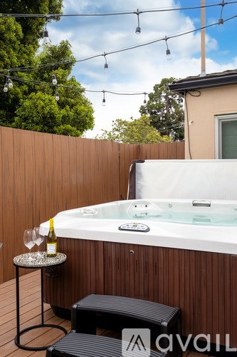 A hot tub is surrounded by a wooden deck and a fence.