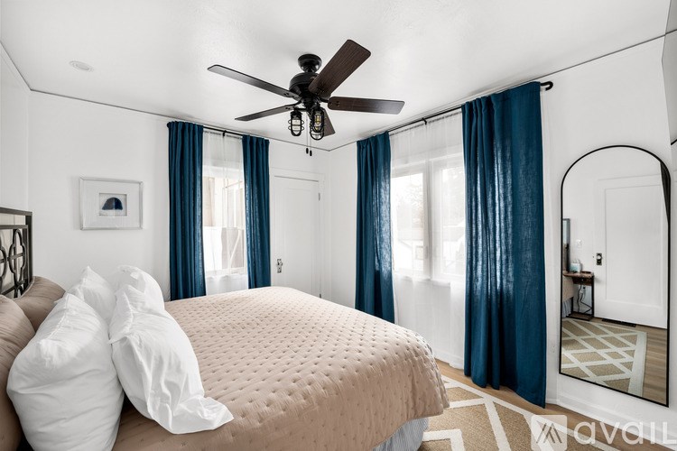 A bedroom with a bed, a ceiling fan, and a mirror.