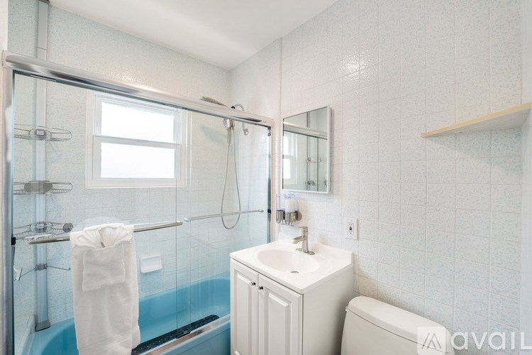 A white towel hangs on a glass shower door in a white bathroom.
