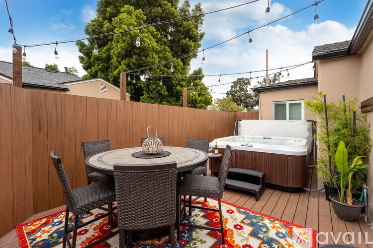 A patio with a round table and chairs, a hot tub, and a potted plant.