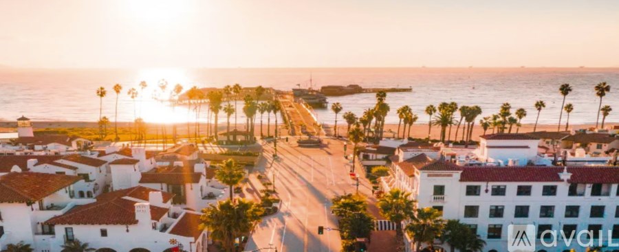A sunset view of a coastal town with palm trees and buildings.