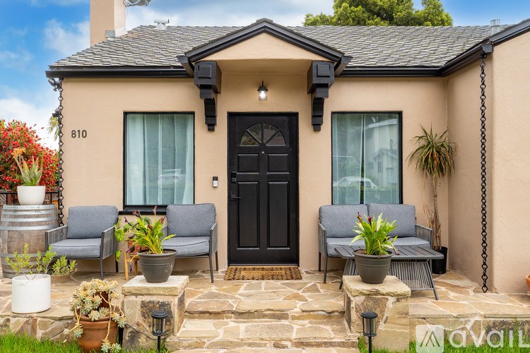 A house numbered 810 with a black door and two grey chairs in front.