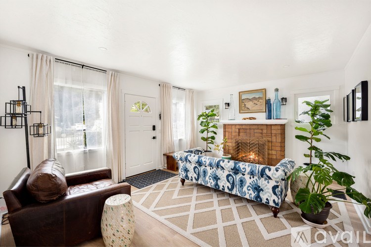 A living room with a brown leather couch, a patterned sofa, a fireplace, and a rug.