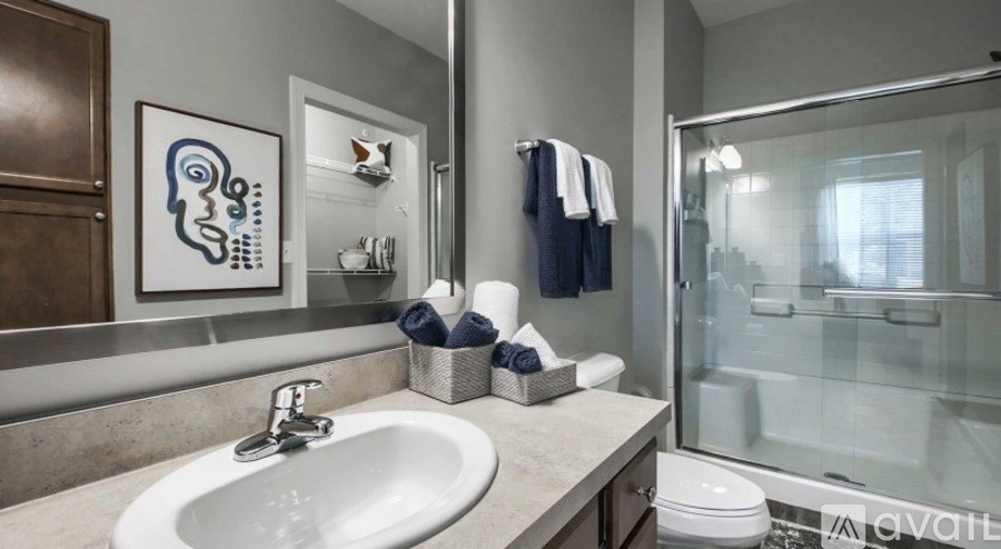 A bathroom with a sink, mirror, toilet, and a shower.