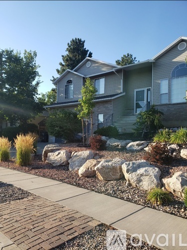 A house with a grey roof and a stone wall in front.