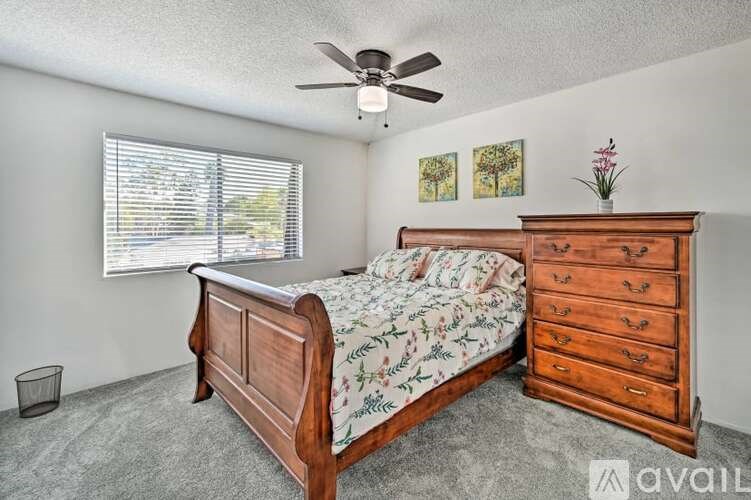 A bedroom with a bed, dresser, and a ceiling fan.