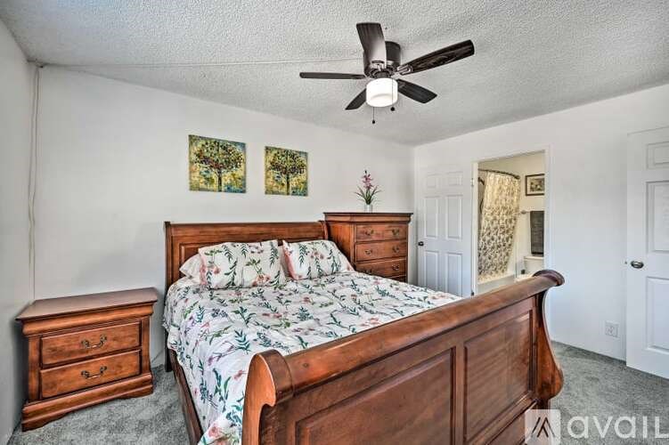 A bedroom with a bed, dresser, and ceiling fan.