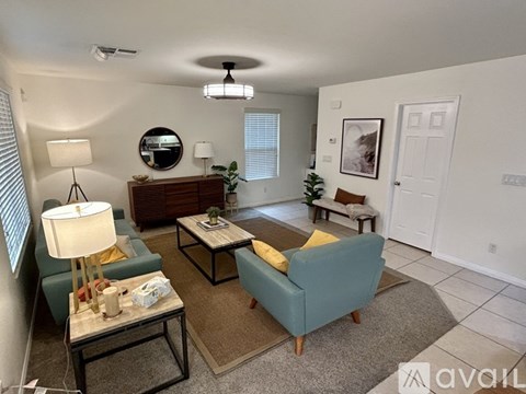 A living room with a couch, chair, and a table with a lamp on it.
