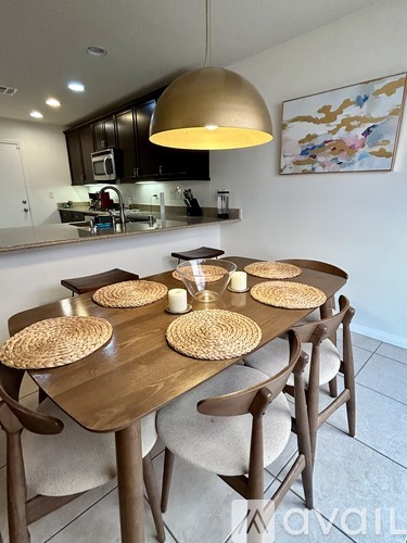 A dining table with a wooden top and woven placemats is surrounded by chairs.