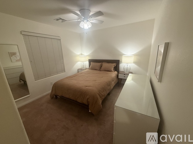 A bedroom with a bed, a ceiling fan, and a wall-mounted light fixture.