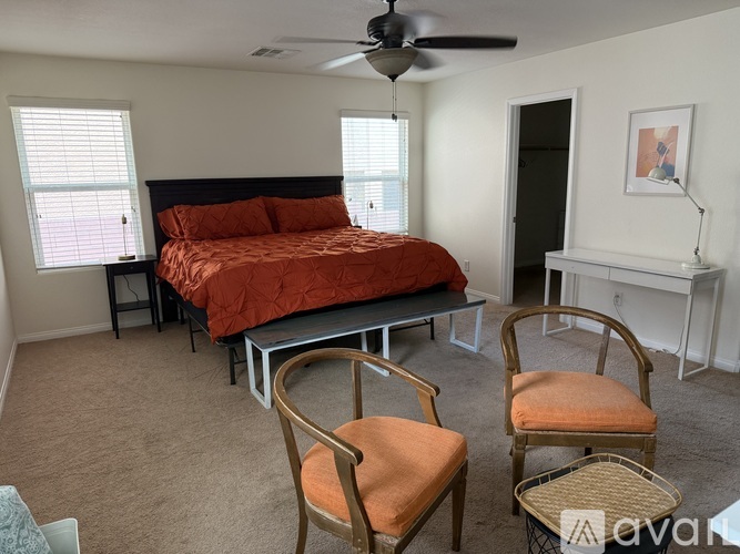 A bedroom with a bed, chair, and a fan.