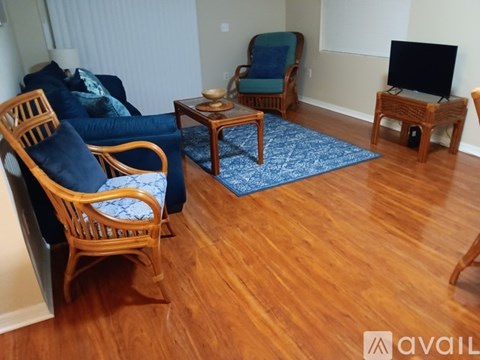 A living room with a blue rug and wooden furniture.