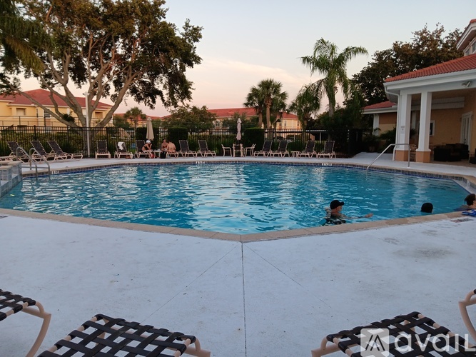A swimming pool with people in it and chairs around it.