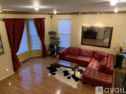 A living room with a red leather couch and a cowhide rug.