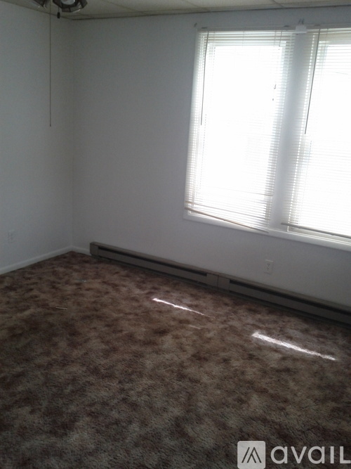 A room with a carpeted floor and a window with blinds.
