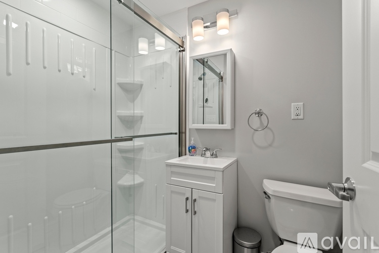 A white bathroom with a glass shower stall and a toilet.