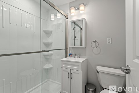 A white bathroom with a glass shower stall and a toilet.