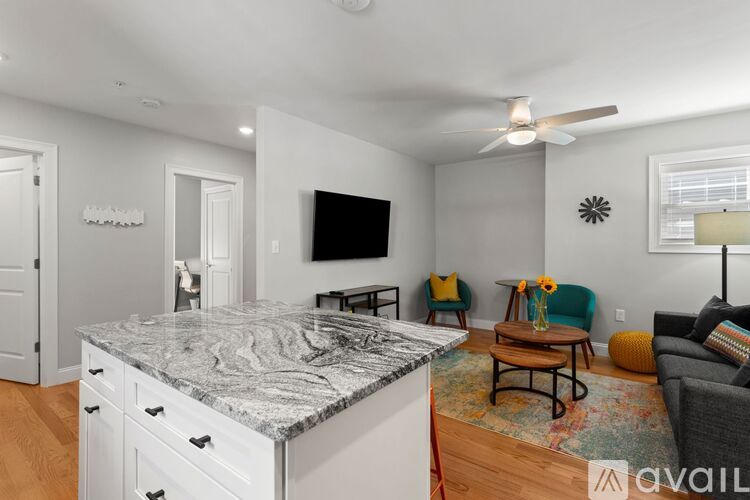A kitchen with a marble countertop and a living room with a couch and a chair.
