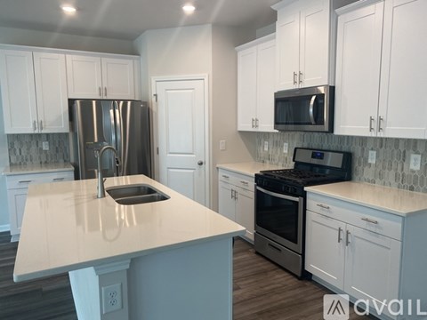 A kitchen with white cabinets and a stainless steel refrigerator.