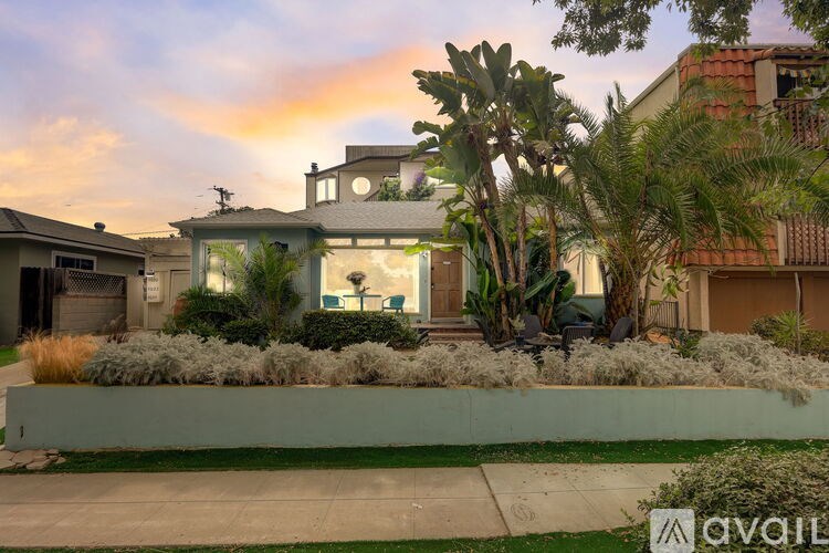 A house with a green lawn and a palm tree in front.