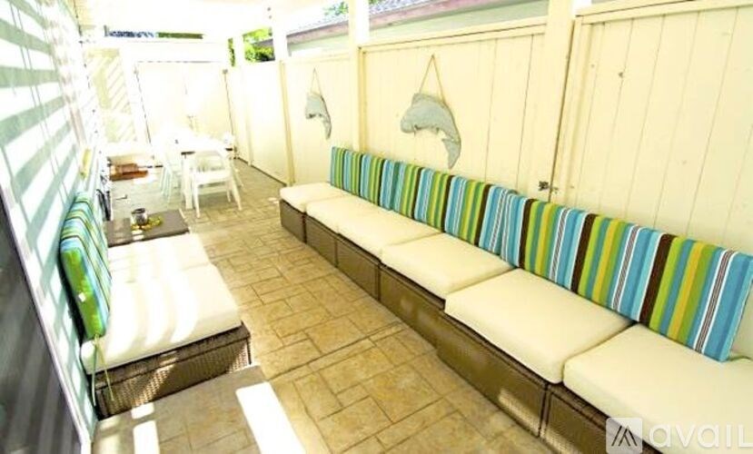 A white couch with a striped pillow is in the center of a room with a white chair and a white table.