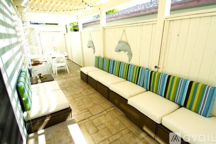 A white couch with a striped cushion is in the middle of a patio.