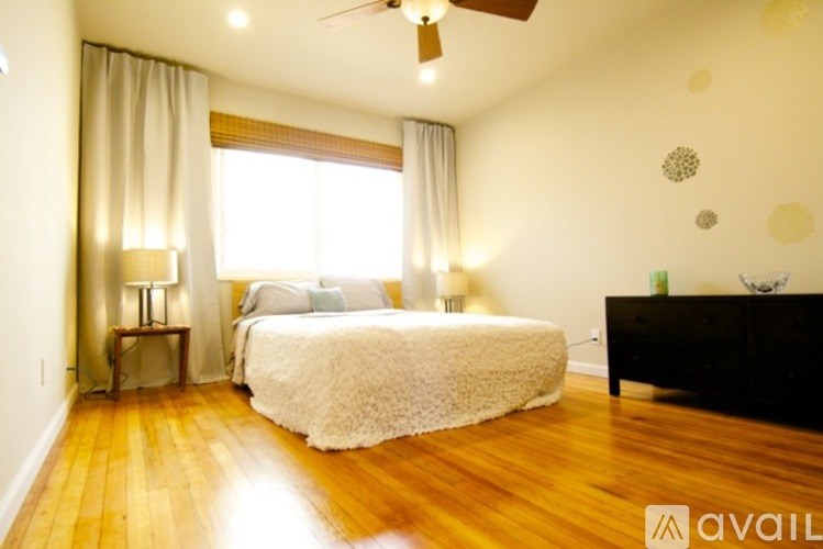 A bedroom with a bed, a nightstand, and a ceiling fan.