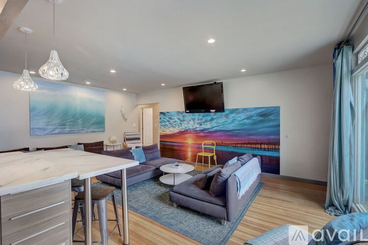 A living room with a large painting of a sunset on the wall.