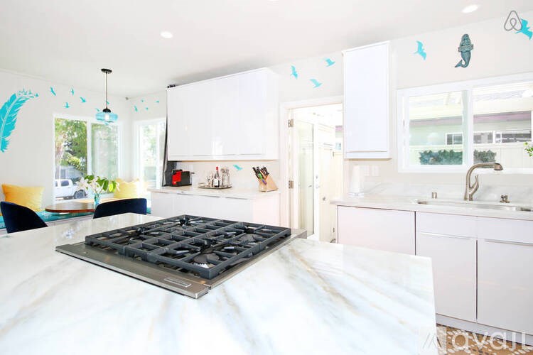 A modern kitchen with a white countertop and a black stove top.