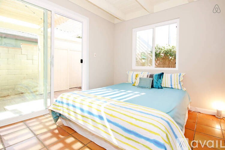 A bedroom with a bed, pillows, and a window.