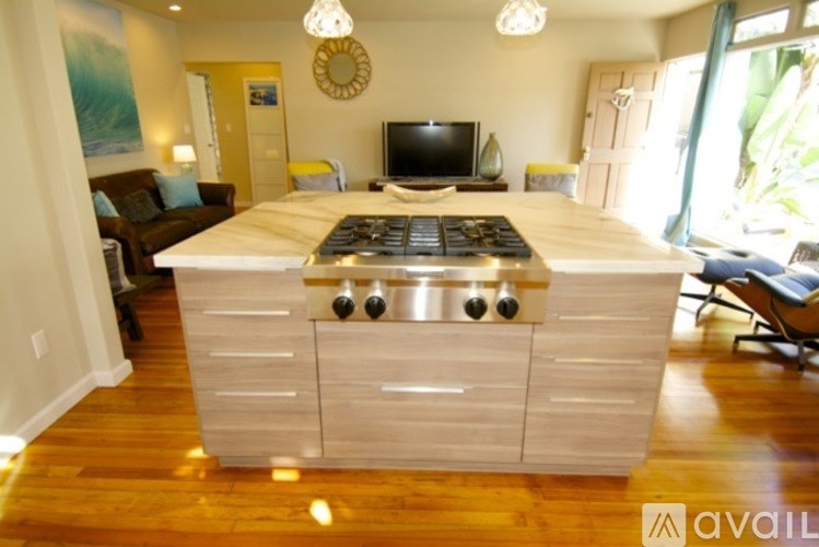 A kitchen island with a stove top in the middle of a living room.